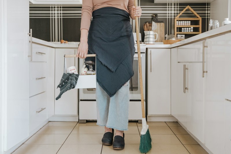 Cleaning technician sweeping a kitchen floor during a deep clean