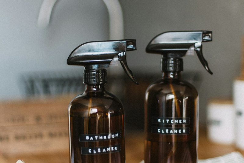 Labeled bathroom and kitchen cleaning spray bottles on a counter